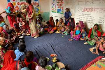 Nutrition Smart village in India: Women and children sit in a group and learn how to have a balanced diet.